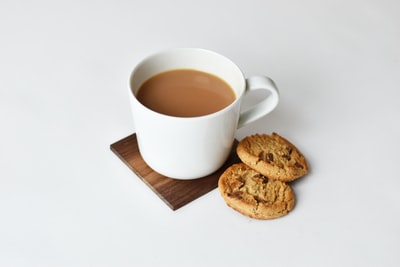 咖啡杯和两块饼干放在棕色杯垫上